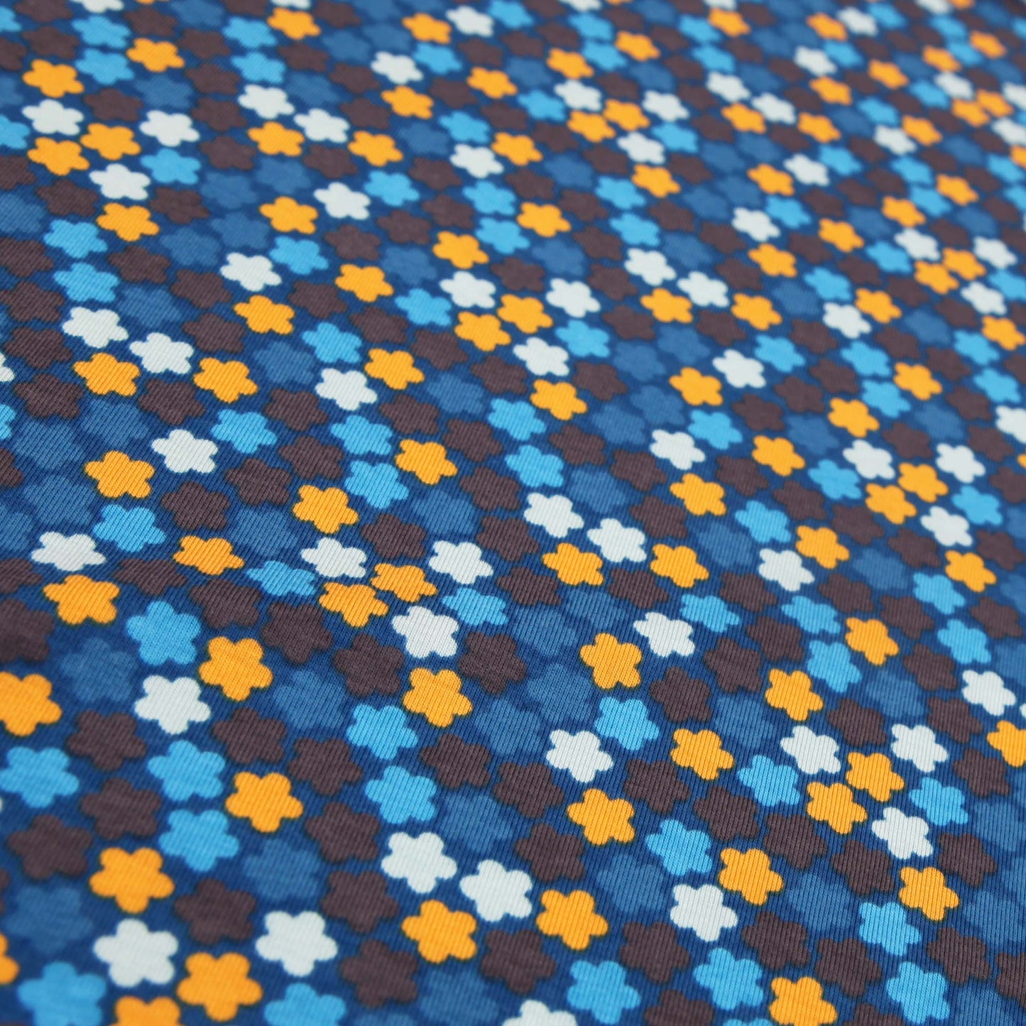 Baumwolljersey mit kleinem Retro-Blumenmuster in Blautönen und Orange auf dunklem Hintergrund.