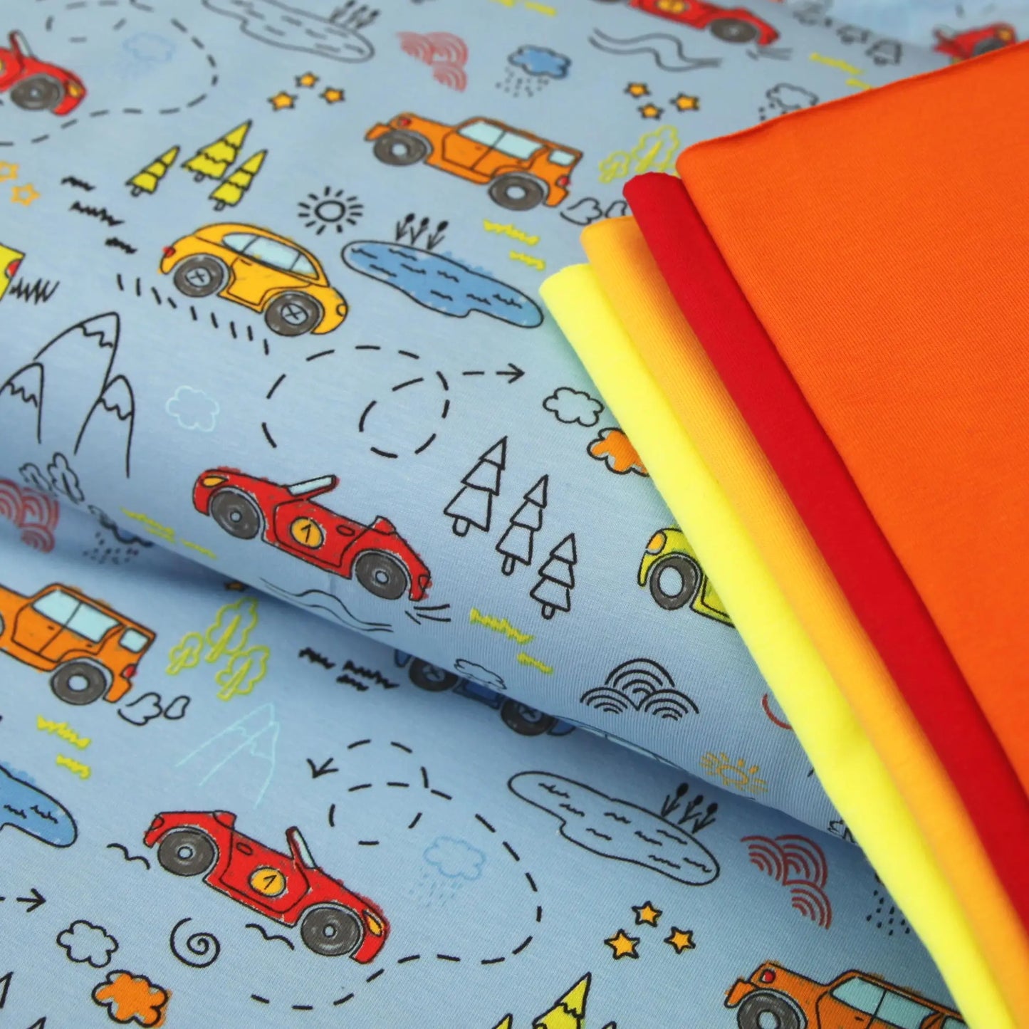 Blauer Baumwolljersey mit bunten Rennwagen, Bäumen und Wolken, vierfarbiger Stoff Stapel.