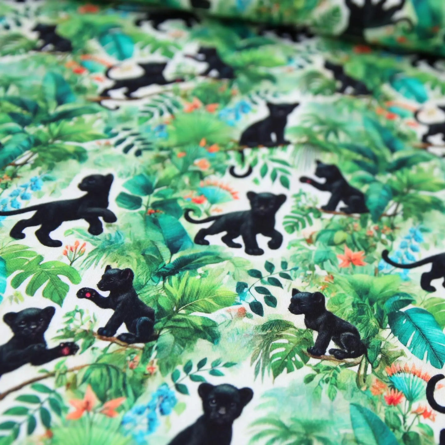 Baumwolljersey mit schwarz gemusterten Baby-Panthern in grünem Dschungel-Design.