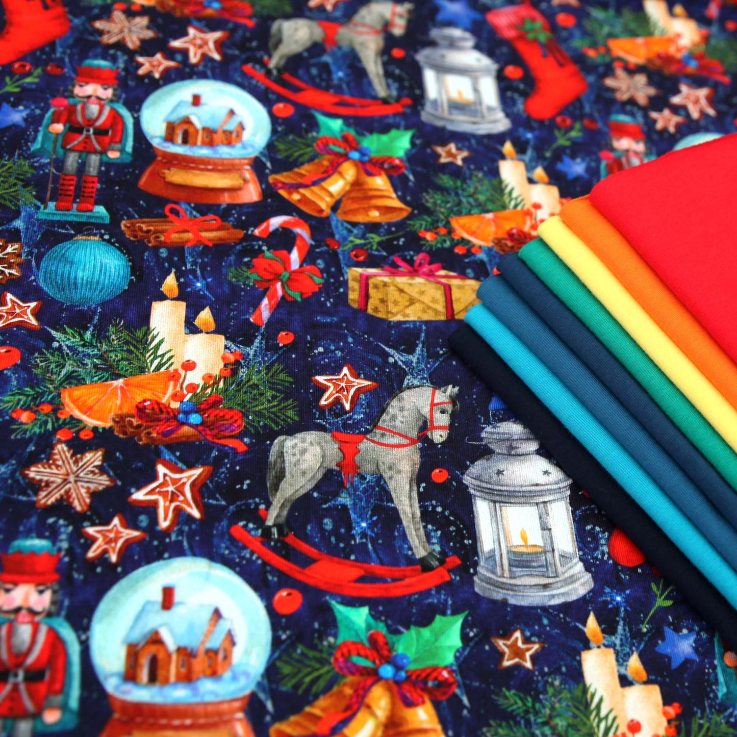 Dunkelblauer Baumwolljersey mit weihnachtlichen Motiven wie Nussknacker, Lebkuchen, Glocken und Laternen, eng bedruckt.