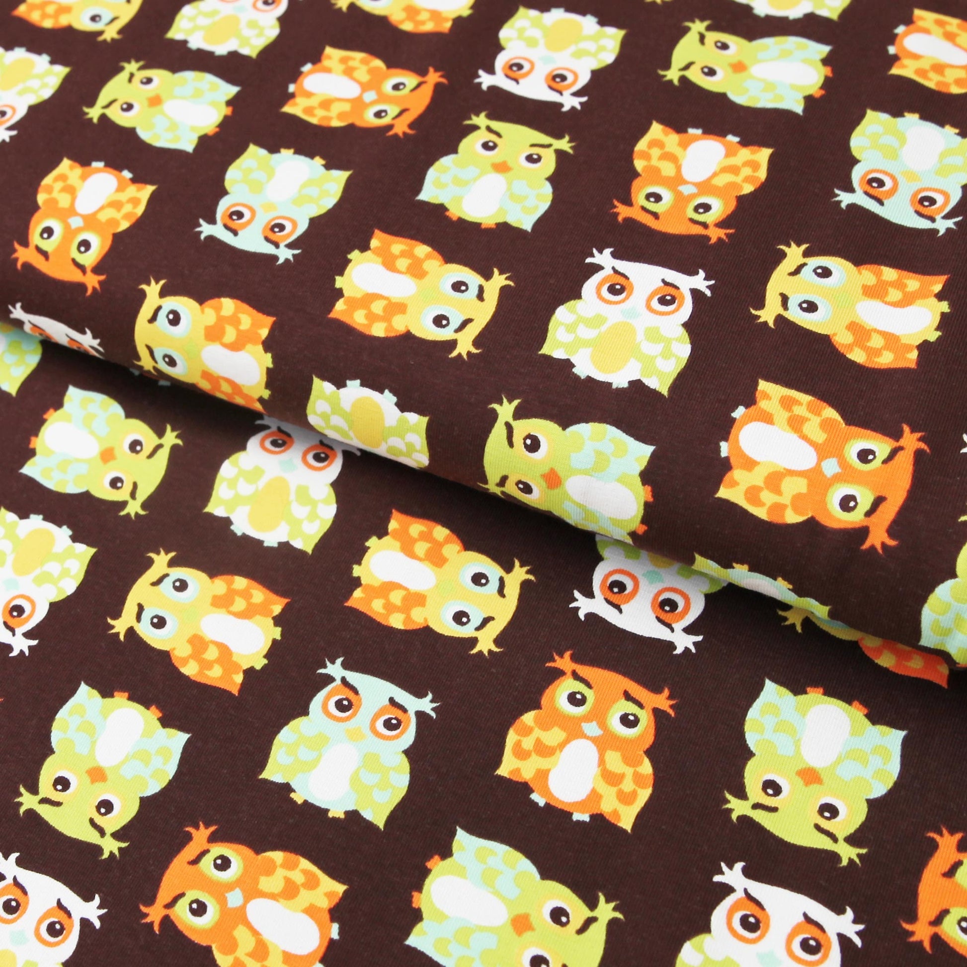 Brauner Baumwolljersey mit bunten Eulen in Orange, Gelb und Hellgrün, verspieltes Muster.